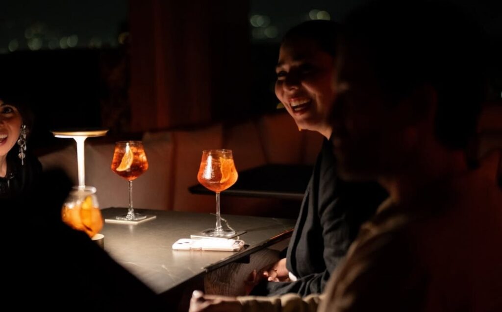 Grupo de personas sentadas en una mesa, disfrutando de copas de cócteles
