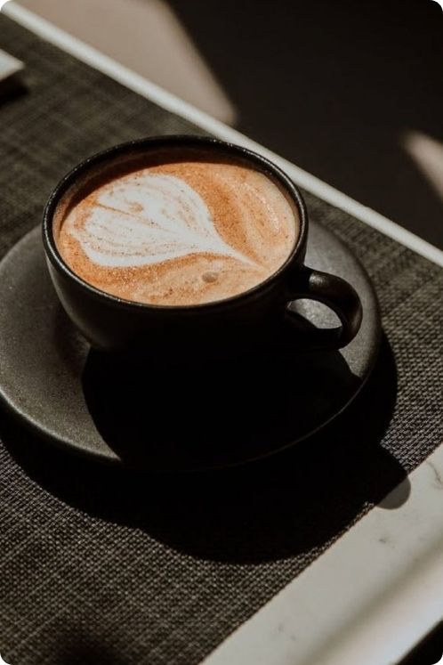 Una taza de café sobre una mesa junto a una laptop