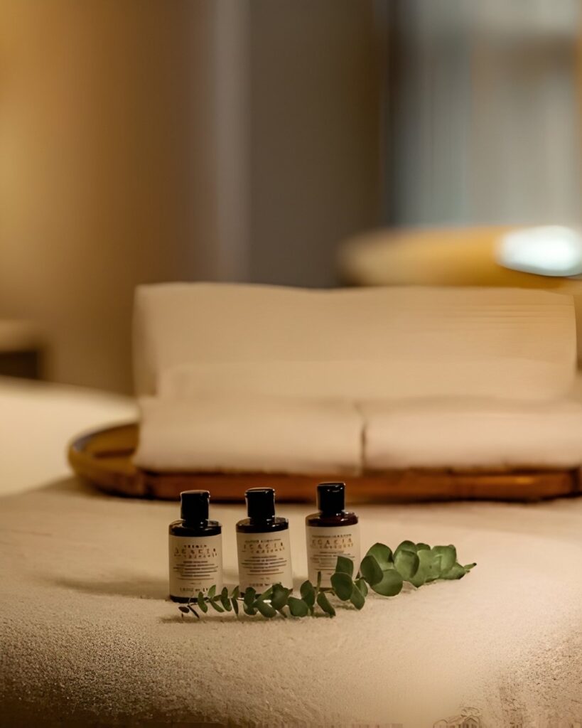 Mesa de masaje con toallas blancas y velas encendidas, creando un ambiente relajante y acogedor.