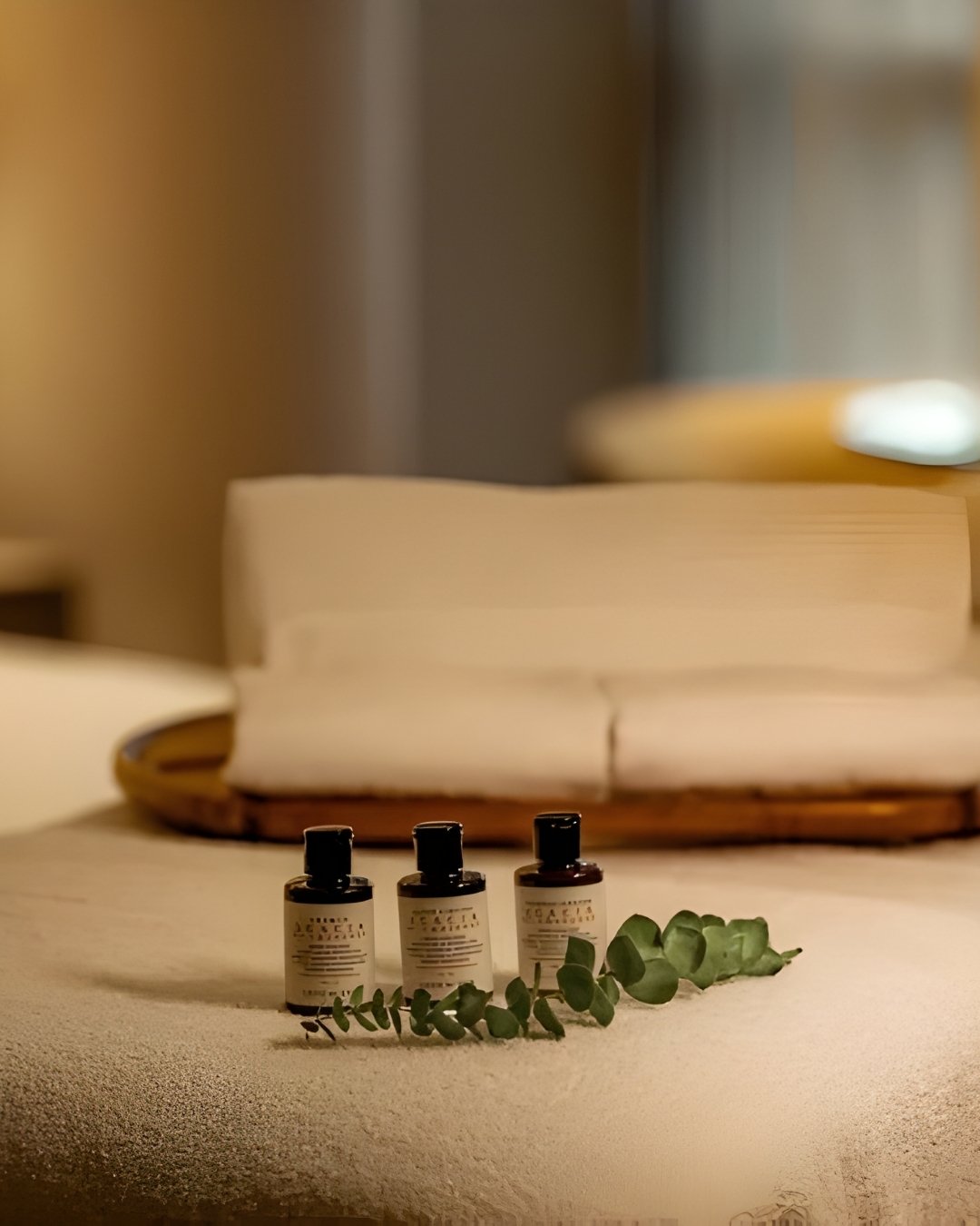 Mesa de masaje con toallas blancas y velas encendidas, creando un ambiente relajante y acogedor.