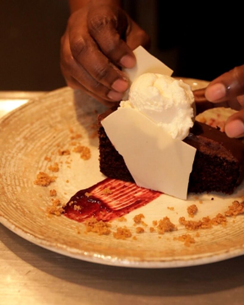 Chef David Suaréz corta un pastel de chocolate acompañado de helado.