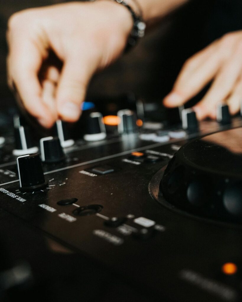 Manos de DJ mezclando en consola en Etro Rooftop Medellín, ambiente nocturno exclusivo con sesiones DJ y música en rooftop elegante