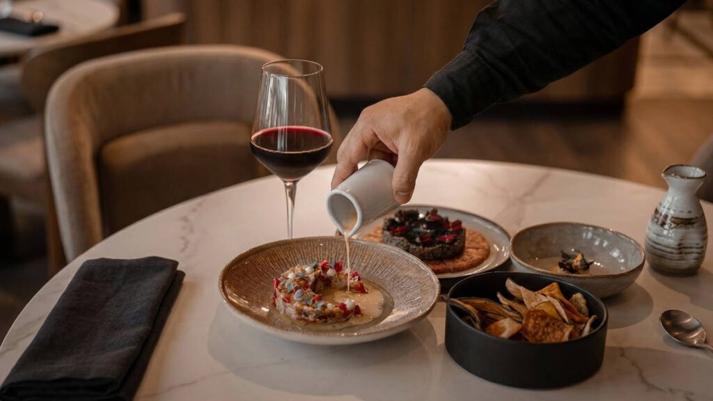 Experiencia gastronómica en hotel de lujo en Medellín con rooftop pool, vino y plato gourmet en ambiente exclusivo.