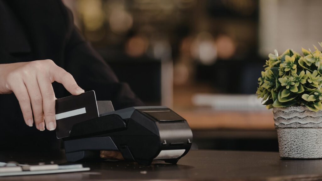 Persona usando una tarjeta de crédito para realizar un pago.