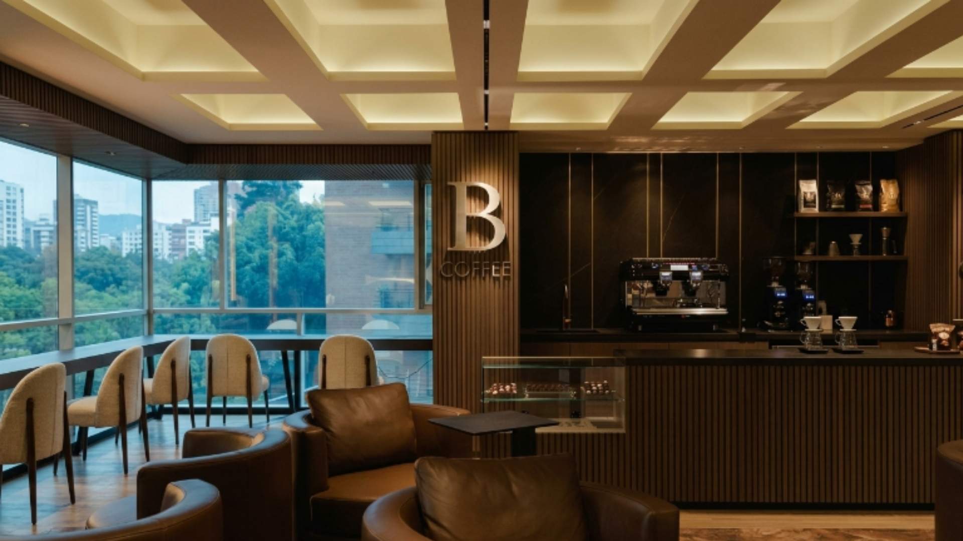 Interior de hotel de lujo en Medellín con cafetería elegante y vista a la ciudad, representando la experiencia y precios del alojamiento premium