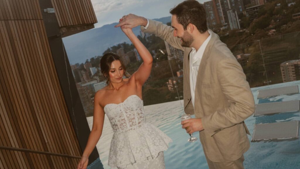 Novios bailando en el balcón de un hotel con vista panorámica de Medellín.