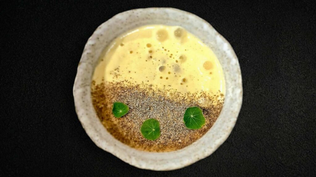 Un tazón de sopa con una hoja verde encima, sin gluten.