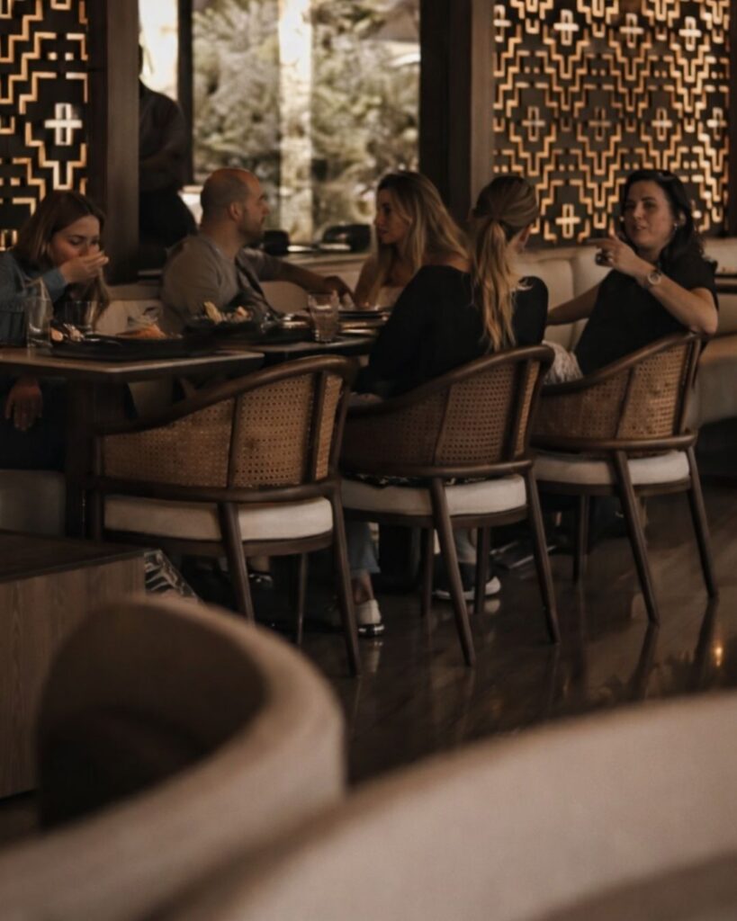 Comensales en un restaurante de lujo, conversando y degustando platos en un entorno refinado.