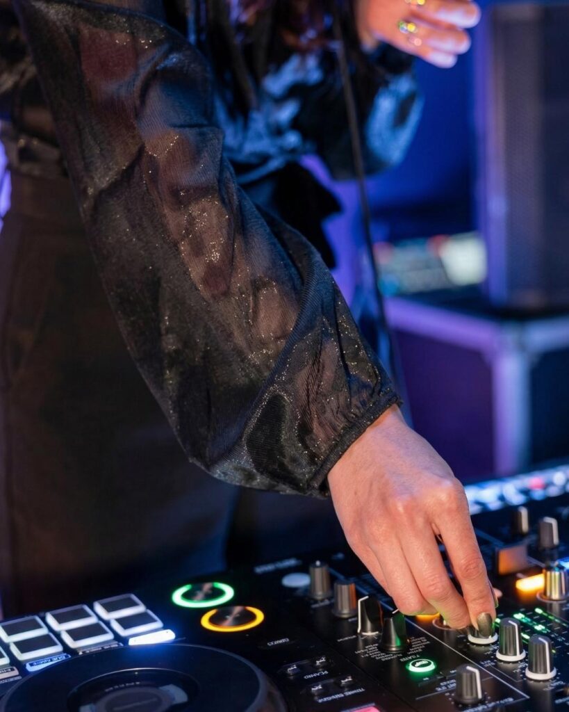 DJ mezclando música en rooftop con buena música en Medellín, consola iluminada y ambiente nocturno vibrante con luces de club.