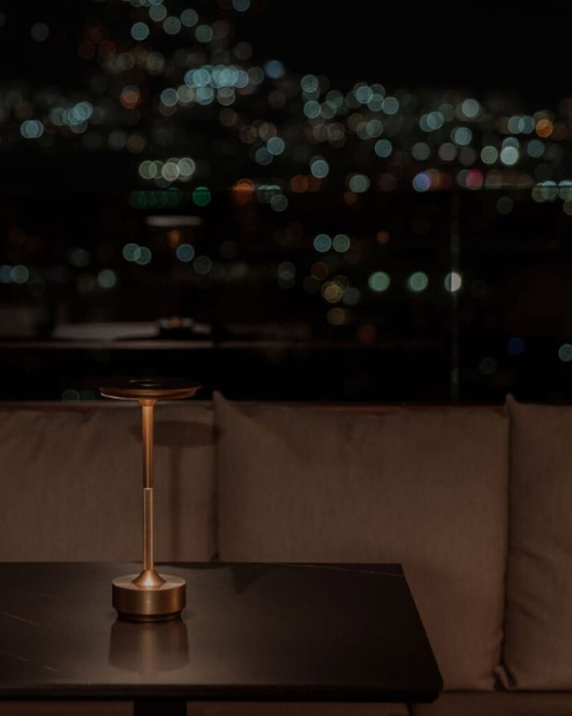 Mesa iluminada en rooftop romántico en Medellín con vista nocturna de la ciudad y ambiente íntimo con luces cálidas desenfocadas.