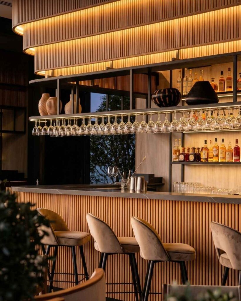 Bar elegante en rooftops con ambiente temático en Medellín, iluminación cálida, barra moderna y selección de licores en espacio sofisticado.