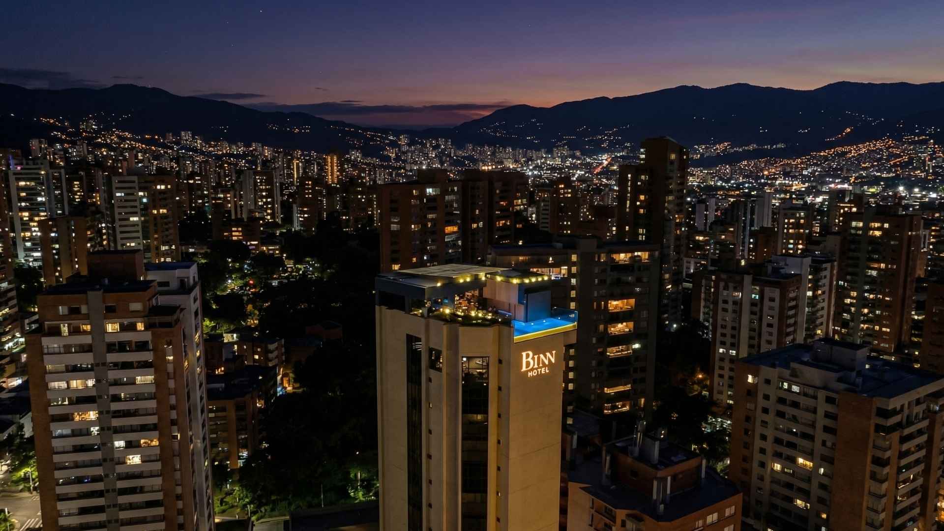 Vista nocturna de Medellín desde un rooftop de lujo con skyline iluminado y ambiente exclusivo.