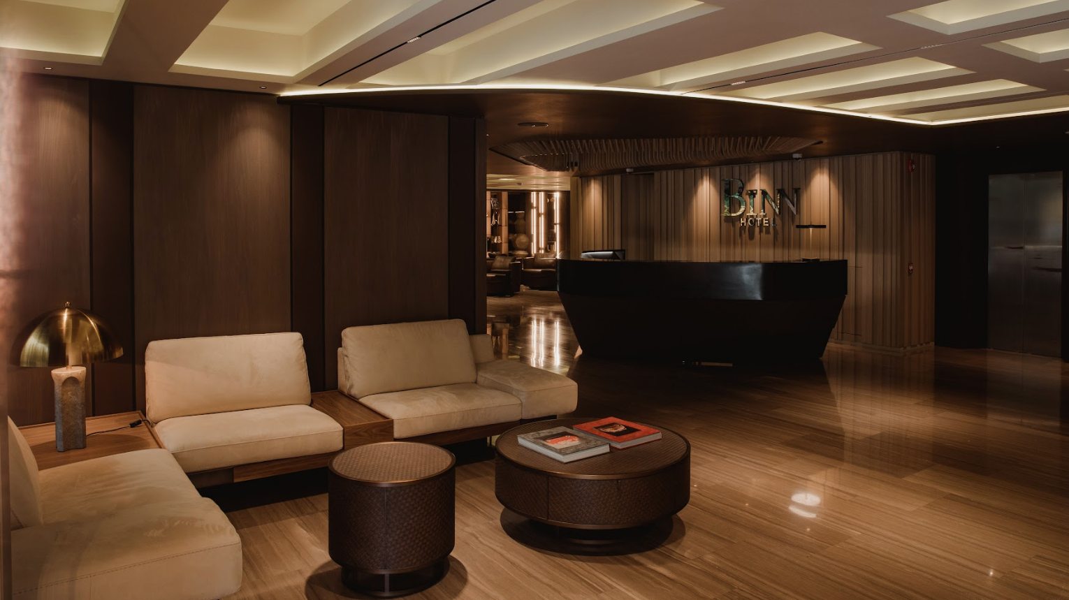 Elegante lobby de BINN Hotel de lujo en El Poblado, Medellín, con zona de estar moderna, iluminación cálida y recepción.