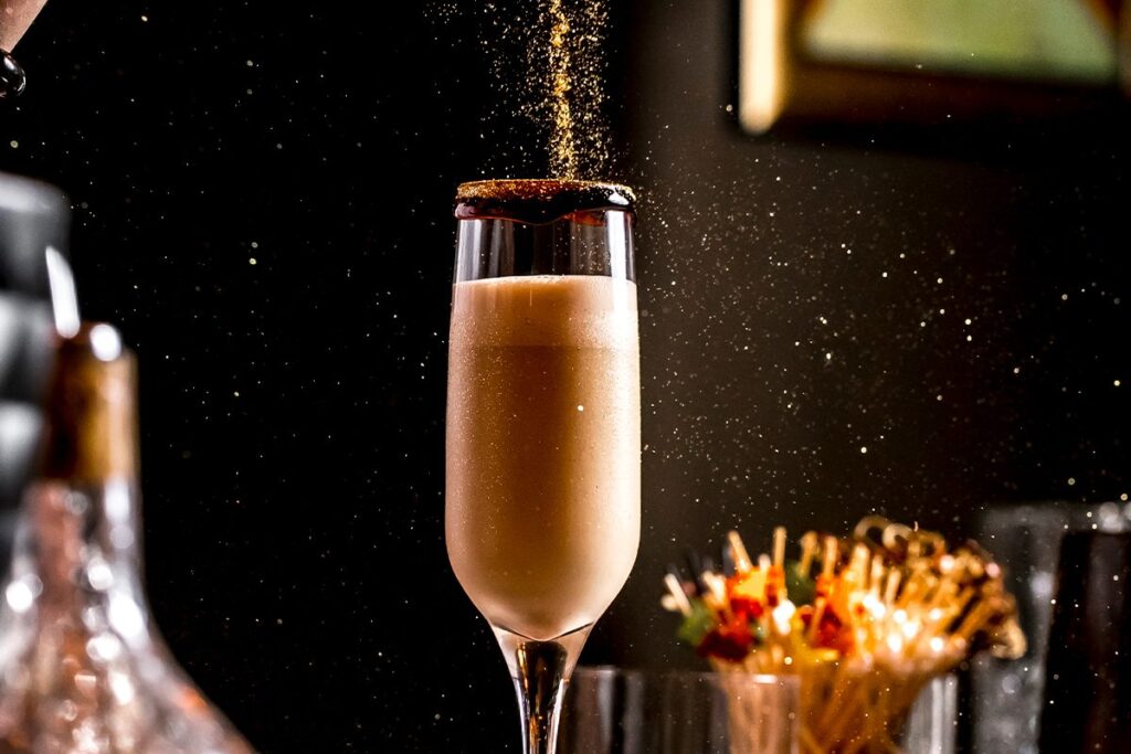 Signature cocktail at La Makha Medellín with golden powder falling, representing the fusion of art and local mixology.