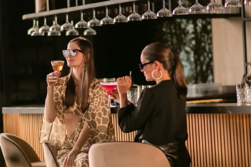 Celebración de cumpleaños en Etro Rooftop Medellín: amigas brindando con cócteles de autor en una barra de lujo.