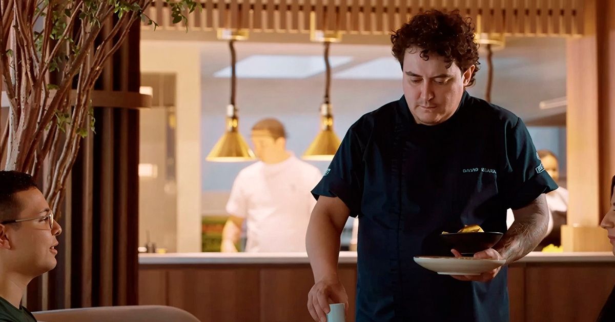 Chef David Suárez Estrada sirviendo un plato en un restaurante moderno con ambiente elegante, destacando una experiencia gastronómica de alto nivel en Orlando