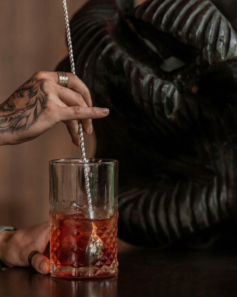 Cóctel artesanal con ingredientes locales servido en rooftop de Medellín con hielo y mezcla elegante en vaso de vidrio texturizado