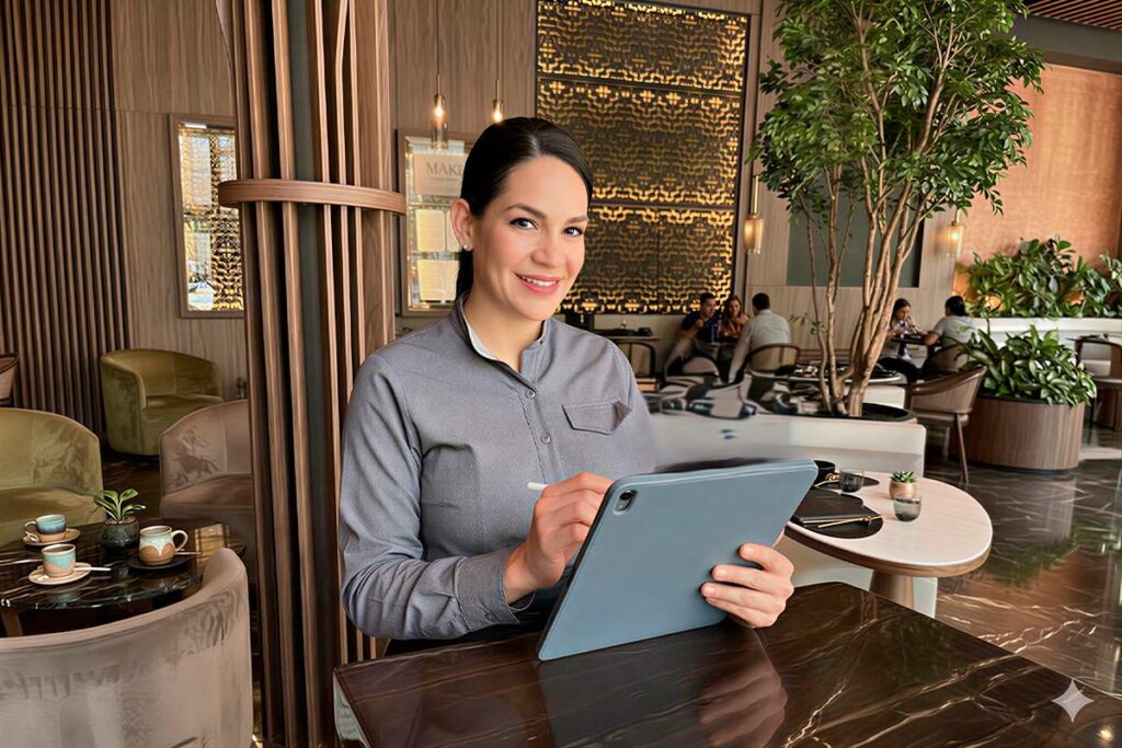 Personal del restaurante La Makha en Medellín gestionando una reserva en una tablet desde el elegante salón principal.