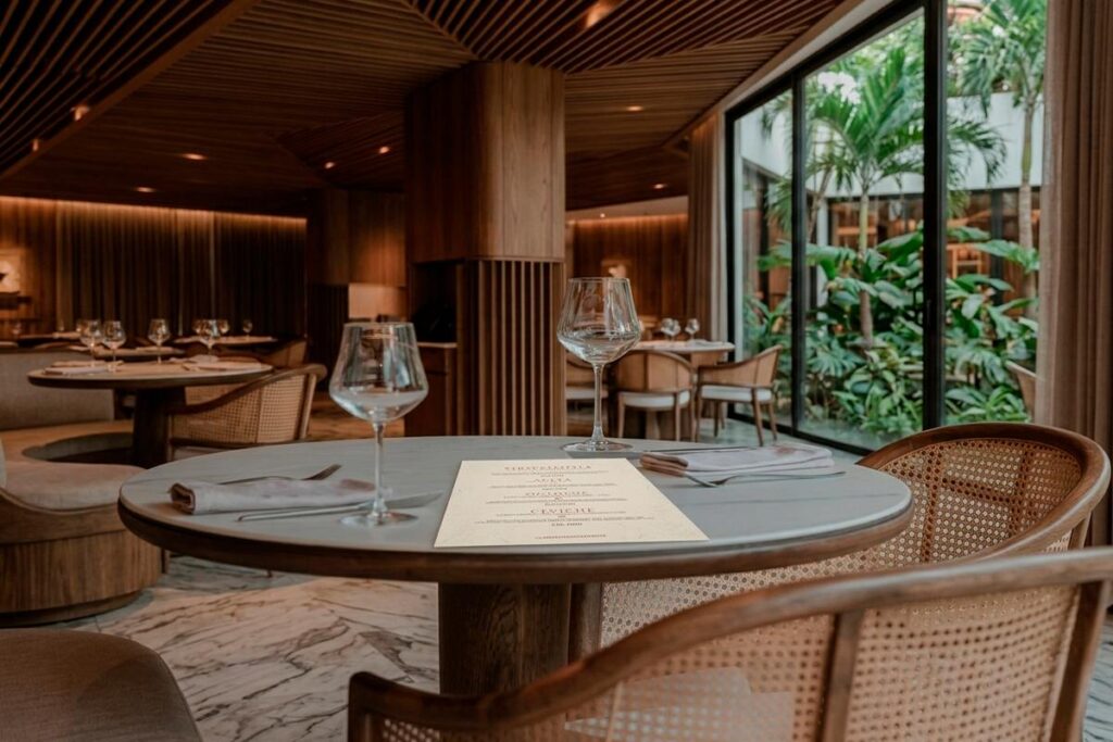 Detalle de una mesa en La Makha Medellín, mostrando la combinación de madera y sillas de mimbre en su diseño.