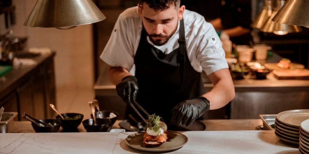 Chef emplatando plato gourmet en cocina profesional con enfoque en gastronomía sostenible en Colombia