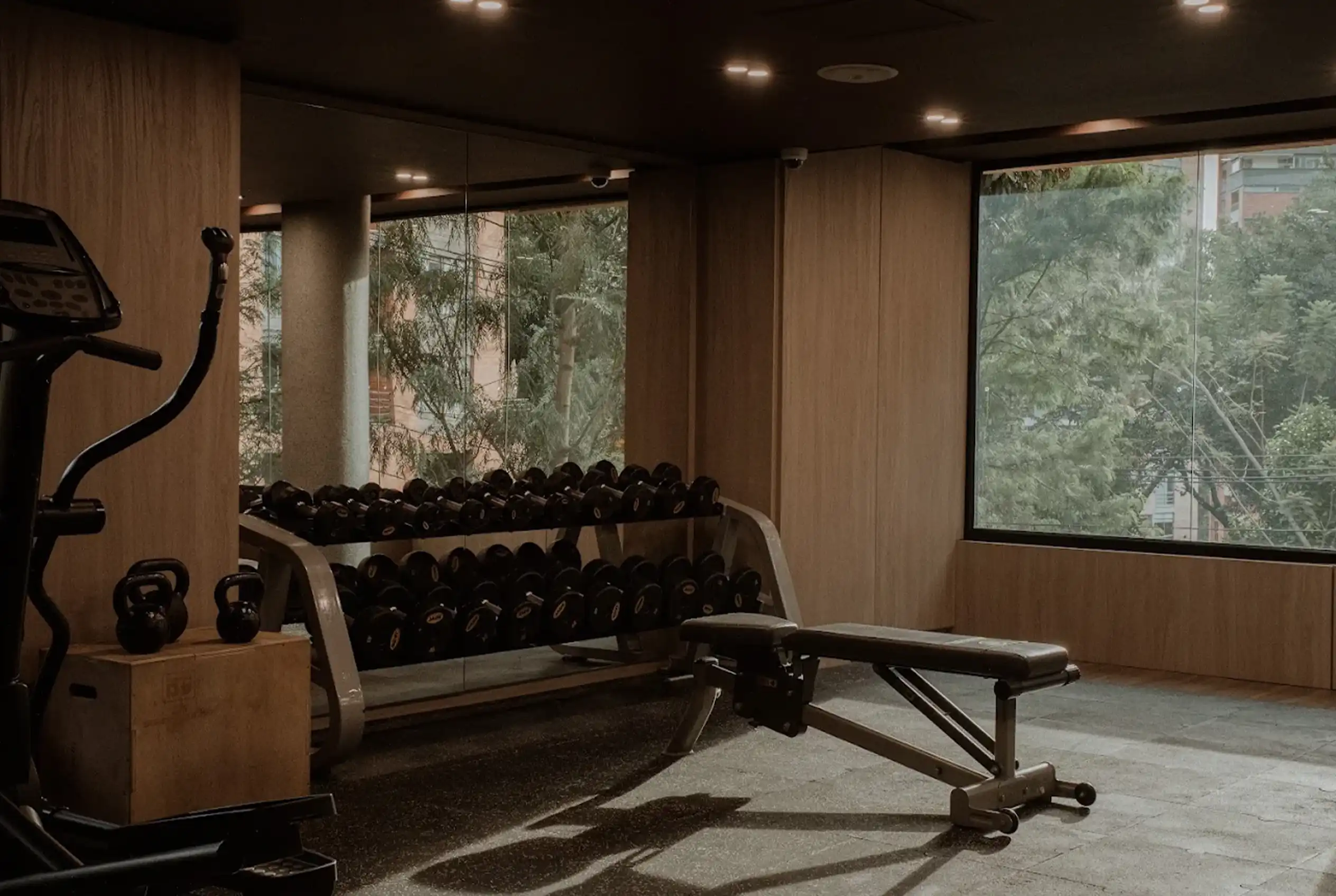 Gimnasio B GYM en Binn Hotel Medellín con zona de pesas, bancos de entrenamiento y grandes ventanales.