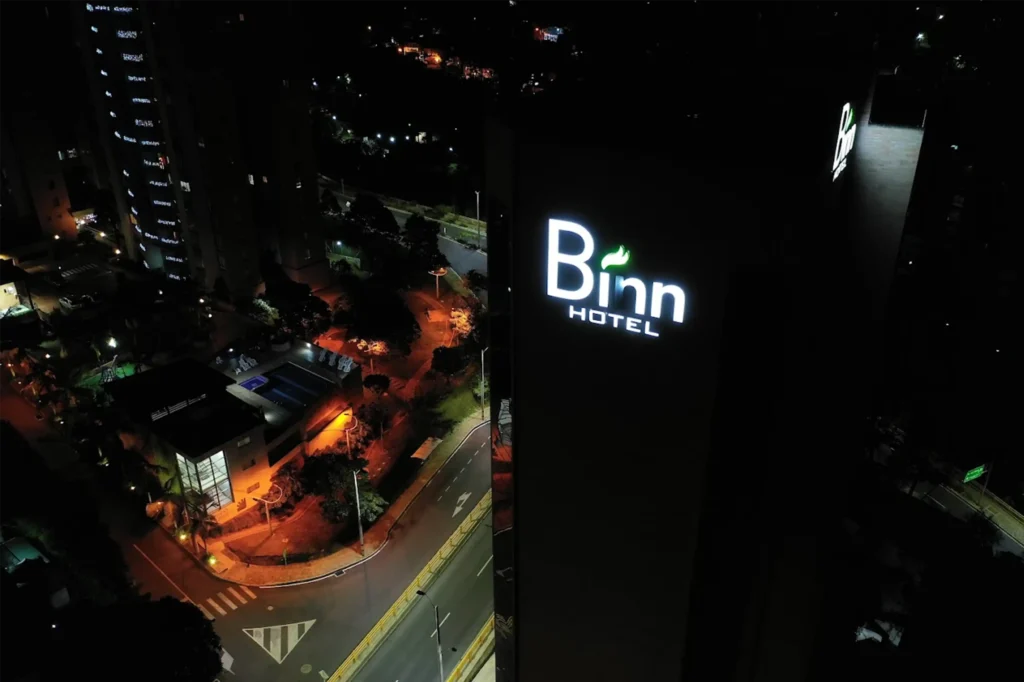 Vista aérea nocturna del Binn Hotel en El Poblado, Medellín, destacando su letrero luminoso y ubicación privilegiada.