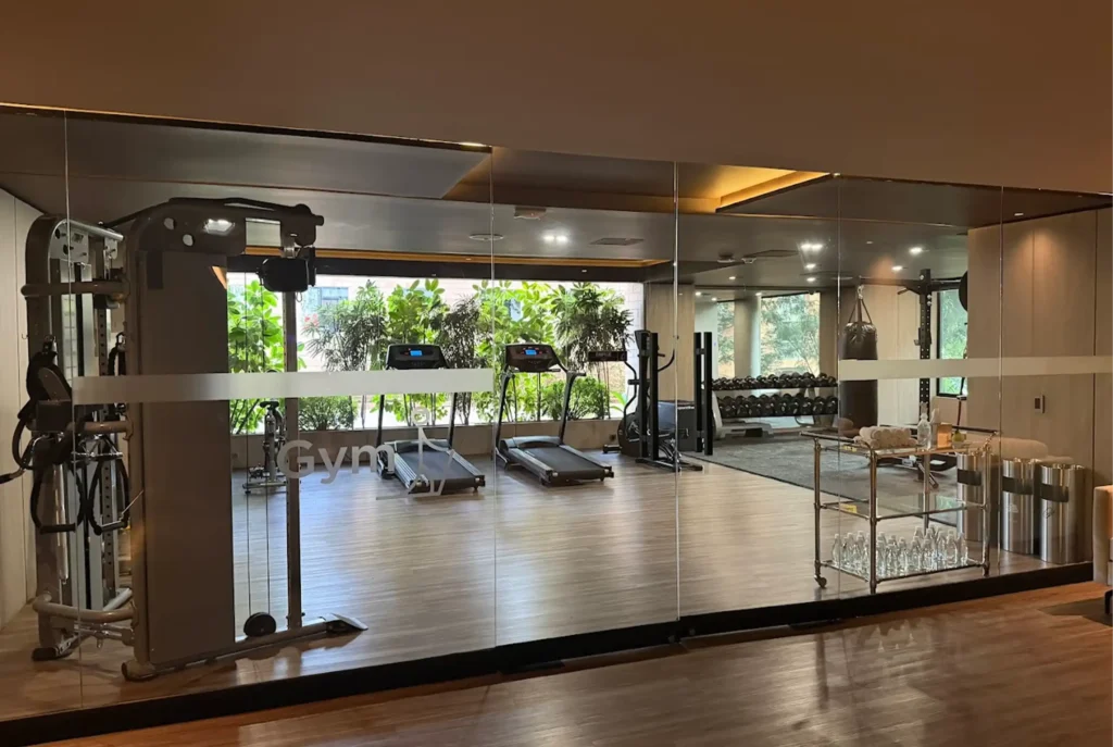 Interior del gimnasio B GYM en Binn Hotel, con máquinas de cardio y fuerza frente a grandes ventanales con vegetación.