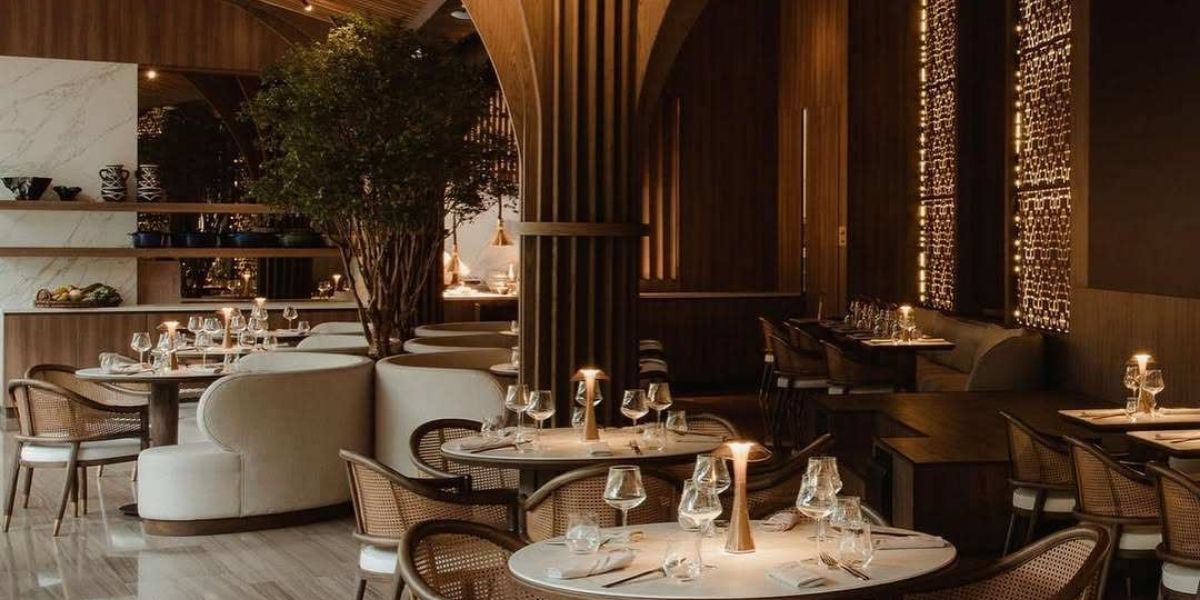 Interior del restaurante La Makha en Medellín durante la Feria de las Flores, destacando su iluminación cálida, mesas elegantes y arquitectura en madera.