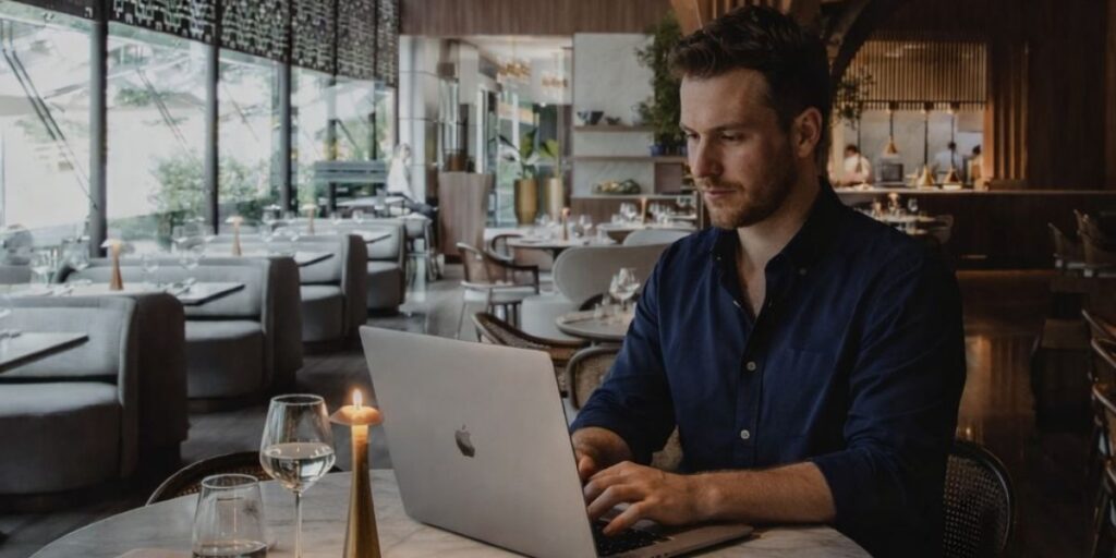 Nómada digital trabajando en su laptop desde el restaurante La Makha en Medellín, disfrutando de un ambiente sofisticado ideal para el trabajo remoto de lujo.