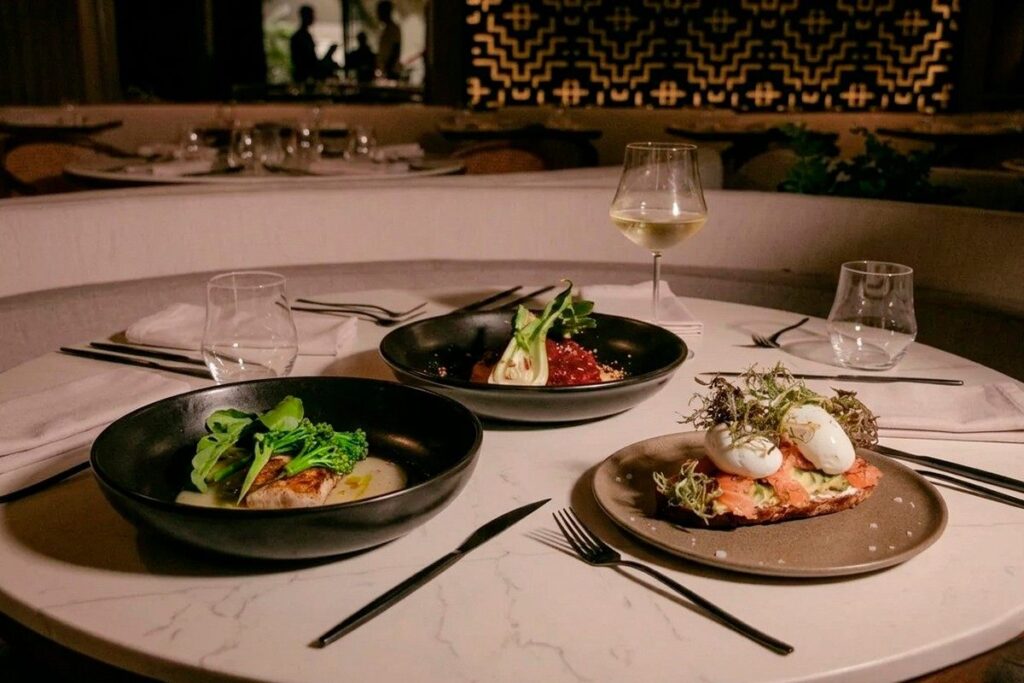 Mesa elegante con platos de alta cocina y copa de vino en un restaurante sofisticado, representando una experiencia de menú degustación gourmet.