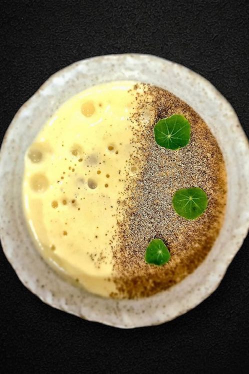 Plato gourmet vegano en el restaurante La Makha de Medellín, con texturas de maíz, polvos vegetales y hojas capuchinas.