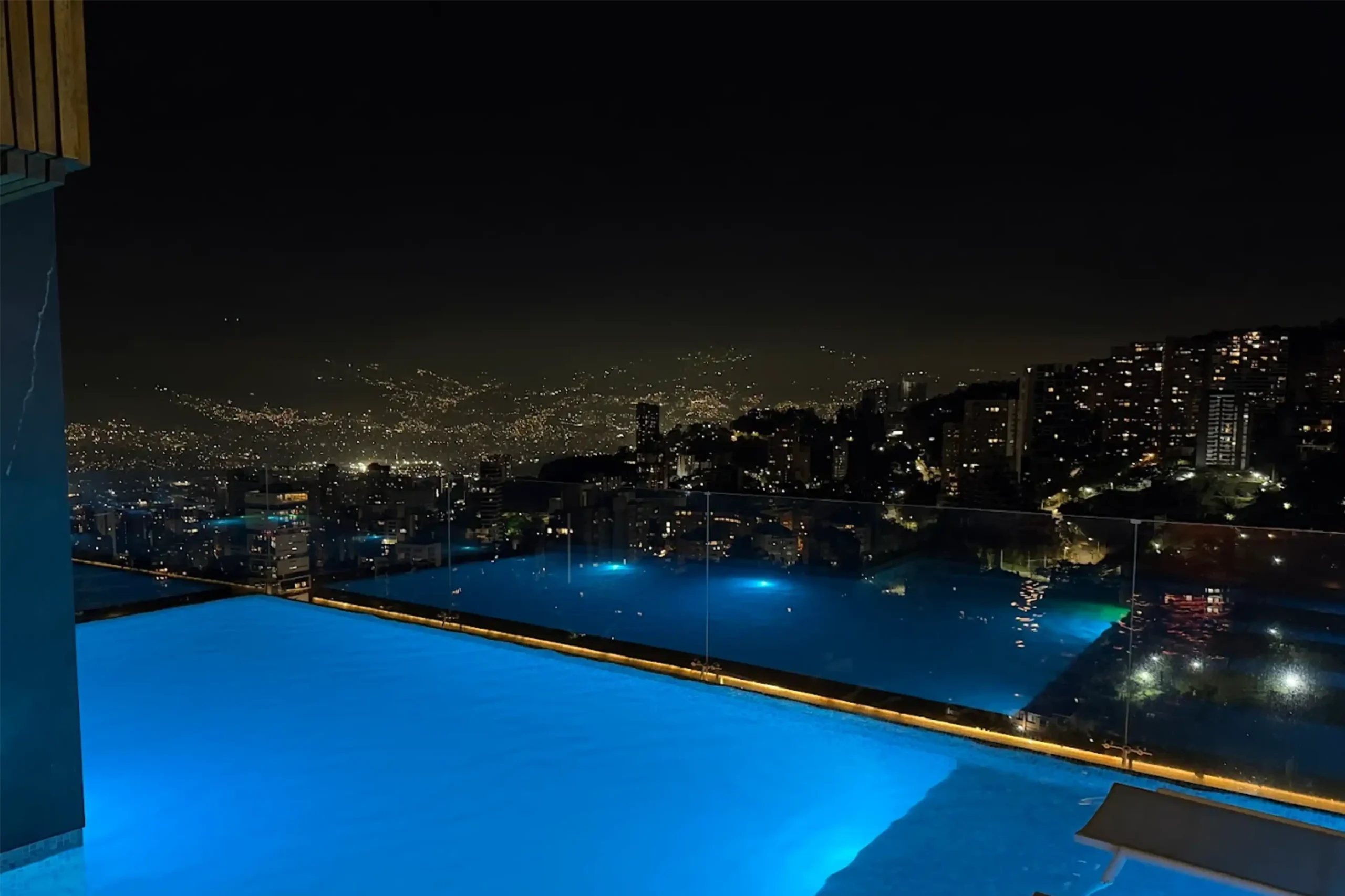 Piscina infinity tipo rooftop en Medellín con iluminación nocturna y vistas panorámicas a las luces de la ciudad.