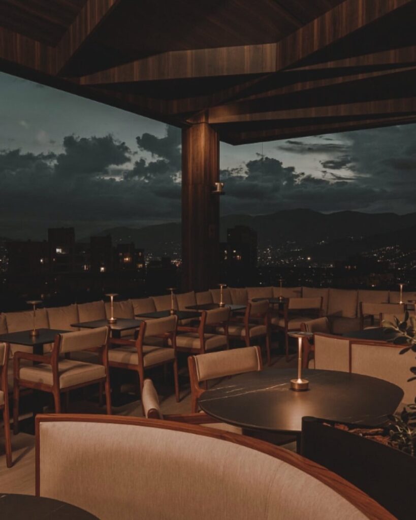 Rooftop en Medellín de noche con diseño moderno, iluminación cálida y vista a la ciudad, ideal para disfrutar comida fusión y experiencias gastronómicas exclusivas