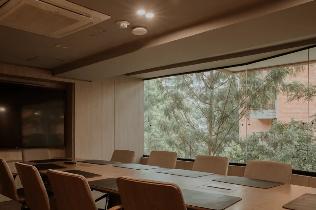 Sala de juntas moderna en un hotel ejecutivo de Medellín con mesa de reuniones, pantallas y vistas a la ciudad.