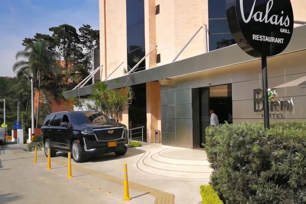 Camioneta de lujo Cadillac en la entrada del Binn Hotel en Medellín, ofreciendo servicio de chofer privado para huéspedes.