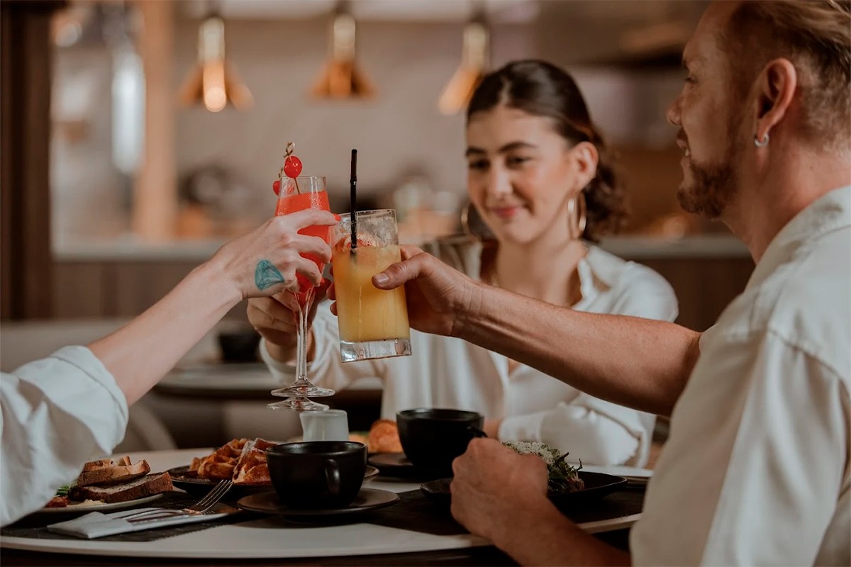 Clientes disfrutando de un brunch con cócteles frutales y café en el restaurante La Makha, destacando el ambiente acogedor y moderno en Medellín.