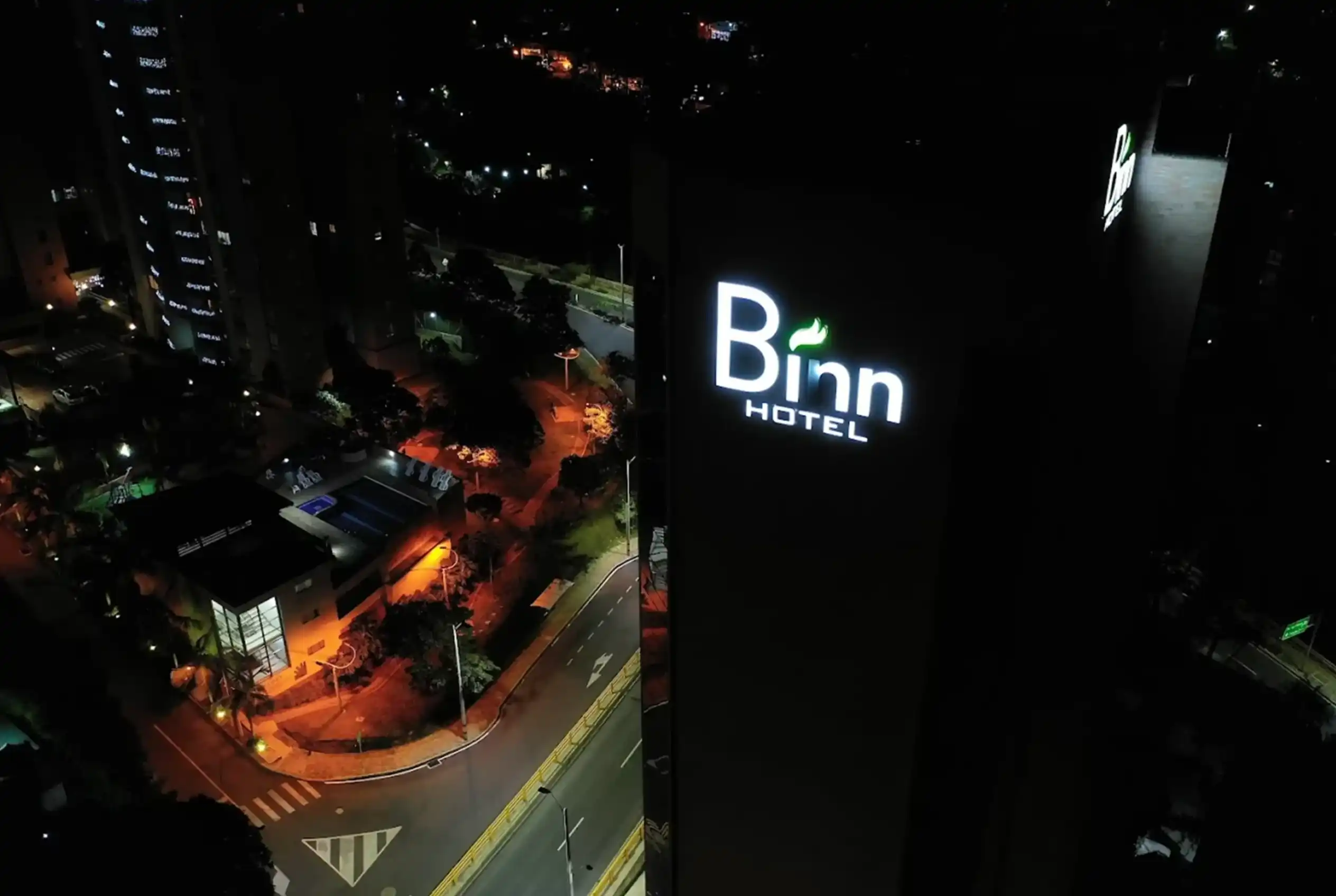 Fachada nocturna y logo iluminado de Binn Hotel Medellín: vista aérea de la ubicación estratégica en El Poblado.