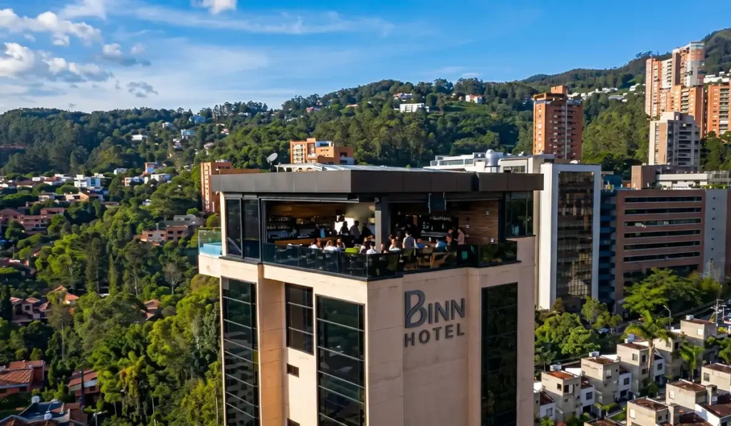 Vista aérea del ETRO Rooftop Bar de BINN Hotel con huéspedes y piscina, clima soleado en Medellín mayo.