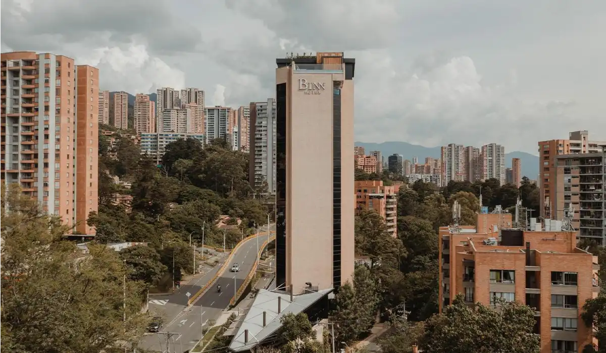 Fachada completa de BINN Hotel en El Poblado rodeada del skyline de Medellín y cordillera.