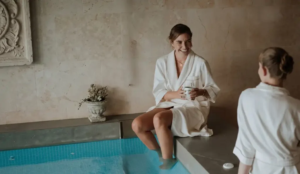 Dos mujeres en batas BINN Hotel junto a piscina de spa, retiro de bienestar para el Día de las Madres en Medellín.
