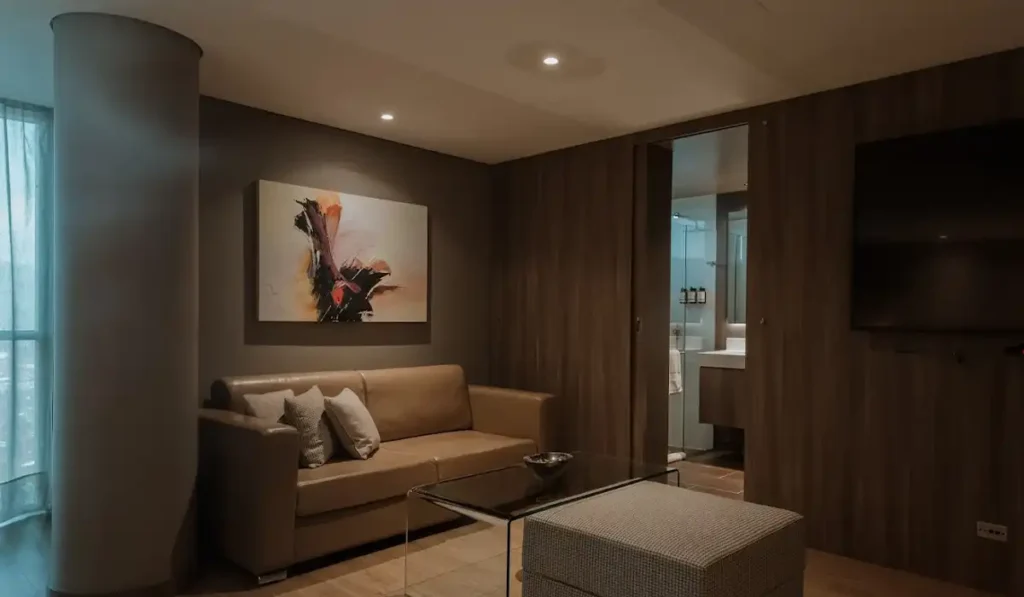 Sala de suite con sofá de cuero, arte abstracto y acceso al baño en BINN Hotel, El Poblado Medellín.