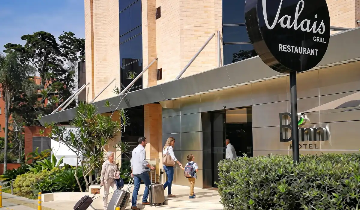Familia llegando con maletas a la entrada de BINN Hotel, viaje familiar en Medellín en mayo.