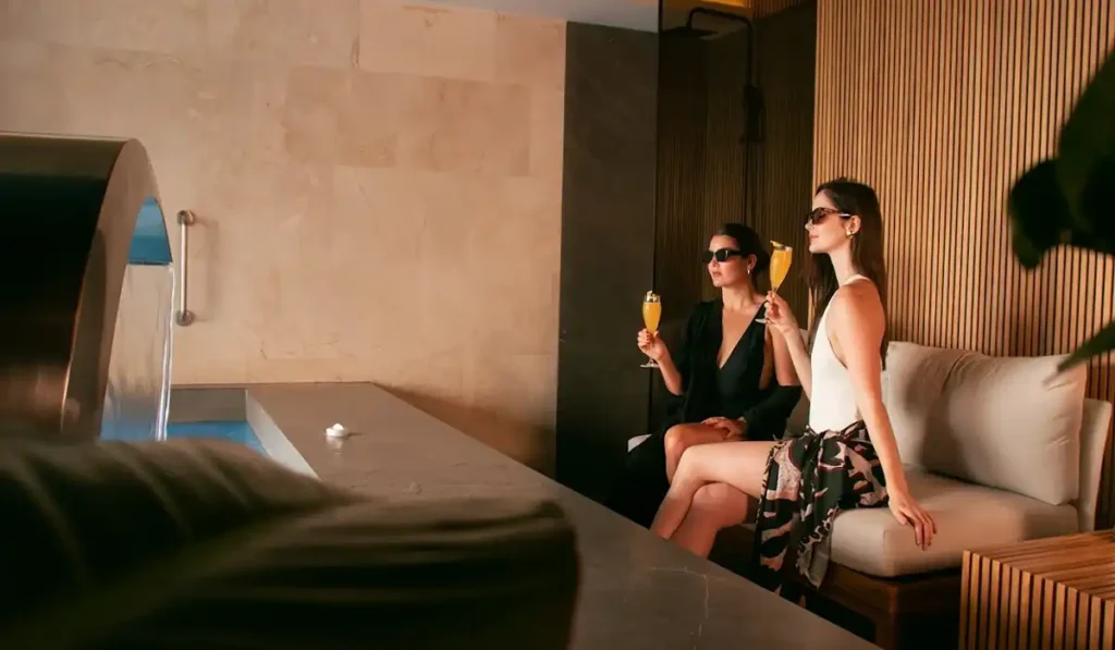 Dos mujeres con cócteles en área de spa y piscina interior de BINN Hotel, plan madre e hija en Medellín.