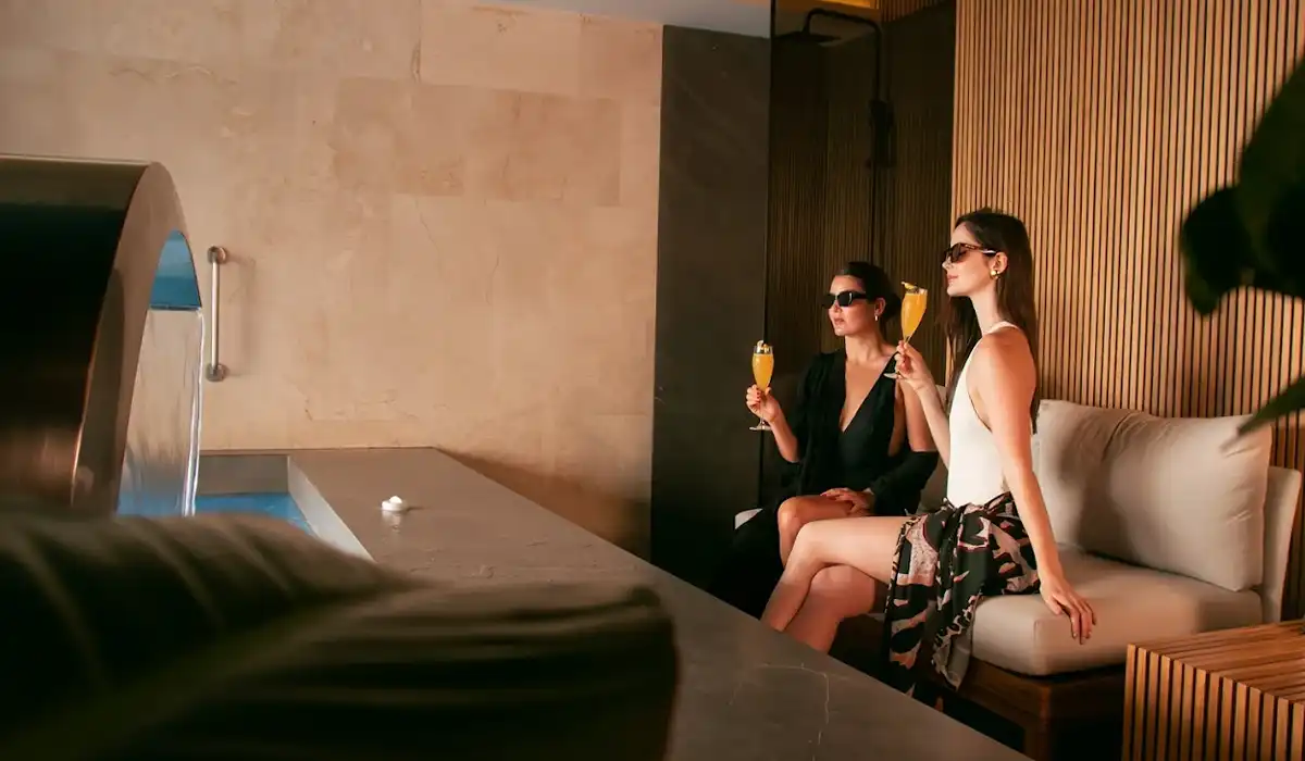 Dos mujeres con cócteles en área de spa y piscina interior de BINN Hotel, plan madre e hija en Medellín.