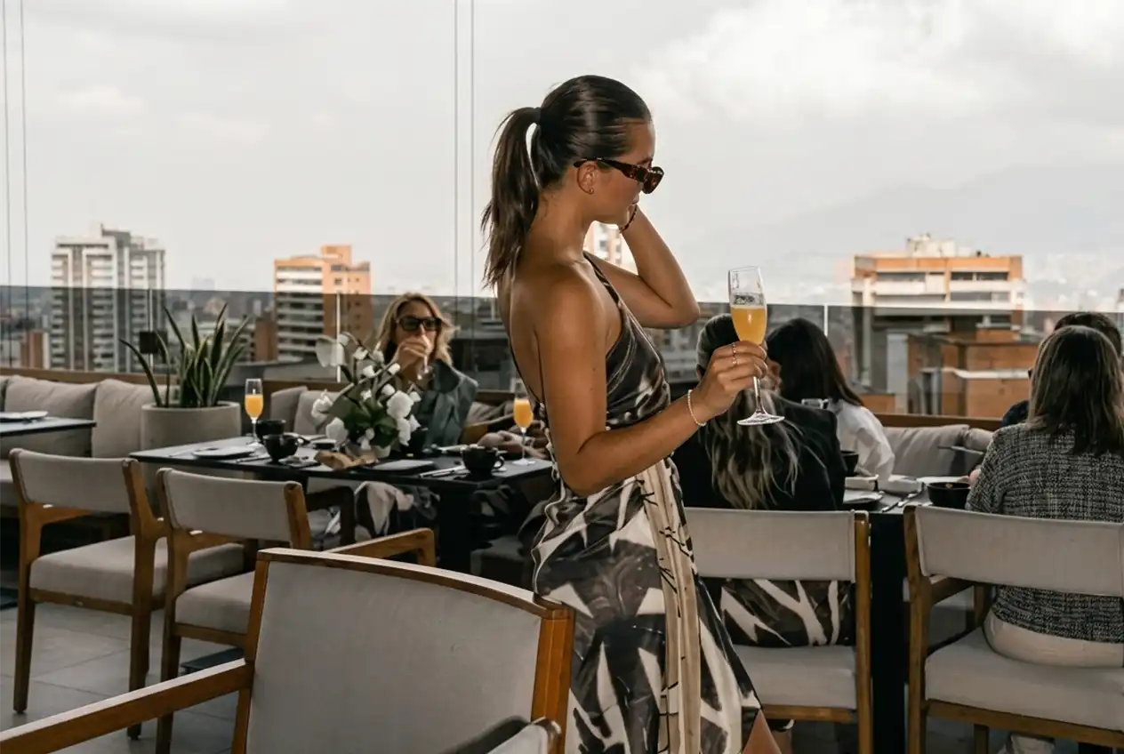 Mujer con copa de champaña en terraza de Etro Rooftop Medellín; ambiente de celebración por el Día de la Madre.
