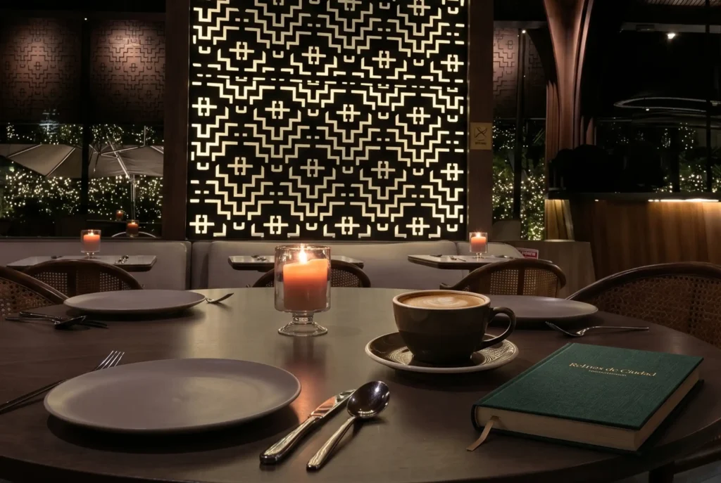 Mesa elegante con café, libro y velas, ideal para comer solo lujo en Medellín en un ambiente íntimo.