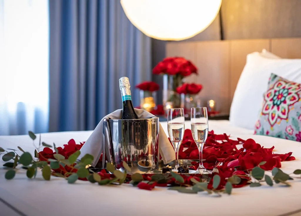 Brindis especial del Día de la Madre en Binn Hotel: champagne en hielera, pétalos de rosas rojas y velas sobre la cama.