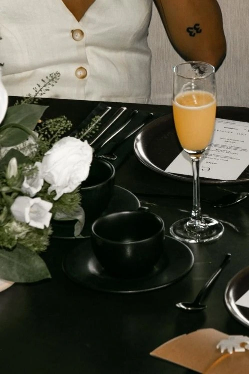 Mesa negra con mimosa, café y flores blancas en afterwork de mayo en ETRO Rooftop, BINN Hotel Medellín.