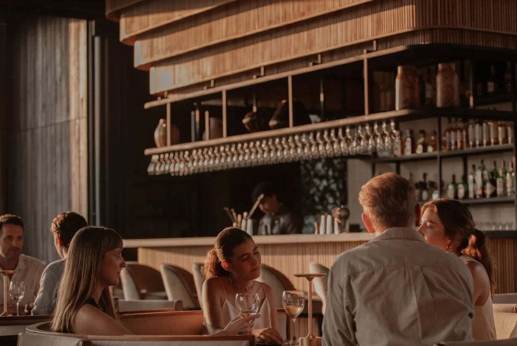 Grupo en sofás con vino blanco en el interior del bar de ETRO Rooftop, cita de mayo en BINN Hotel Medellín.