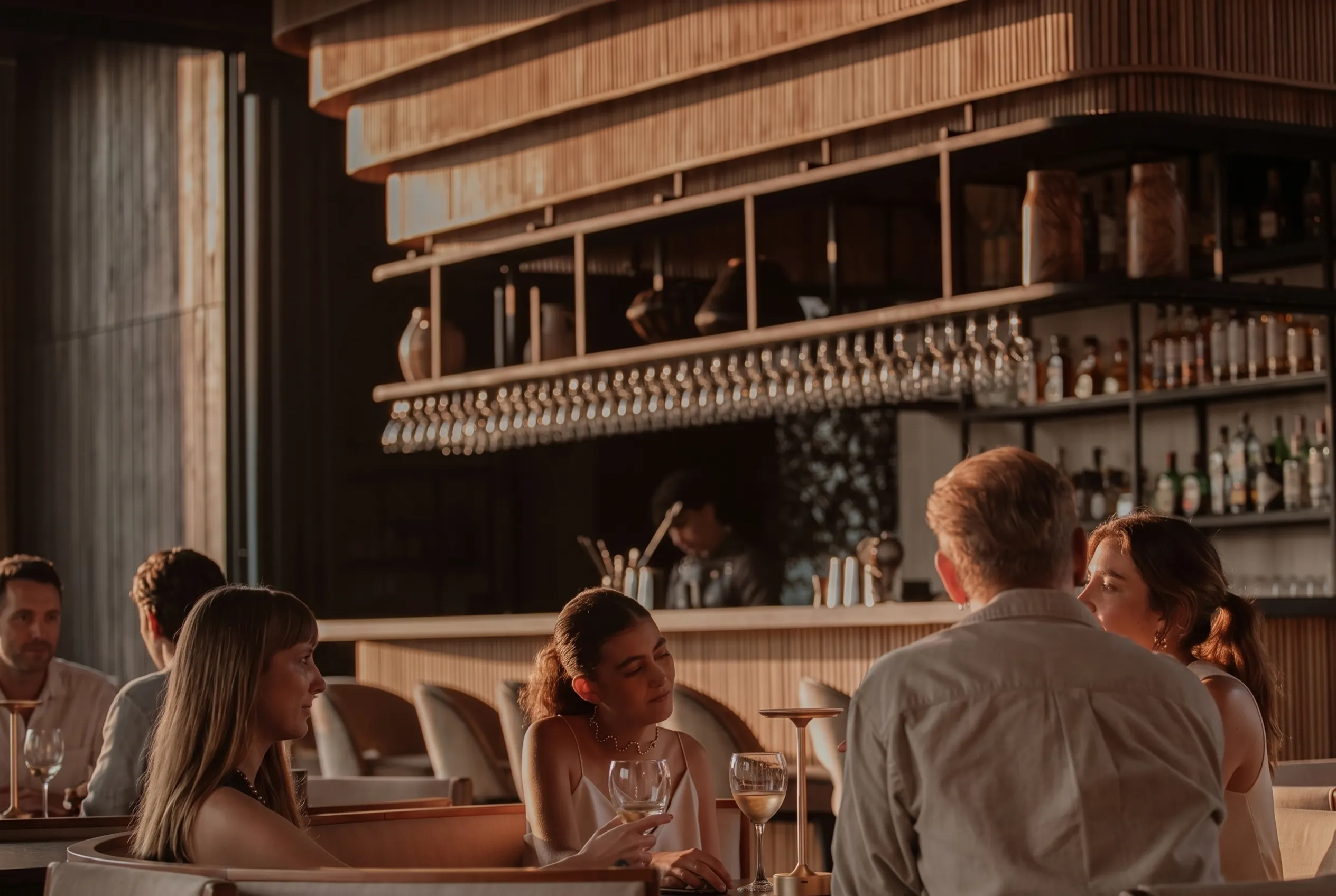Grupo en sofás con vino blanco en el interior del bar de ETRO Rooftop, cita de mayo en BINN Hotel Medellín.